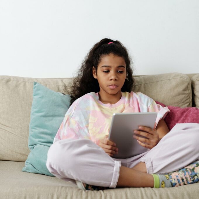 Teen girl holding tablet sitting on couch